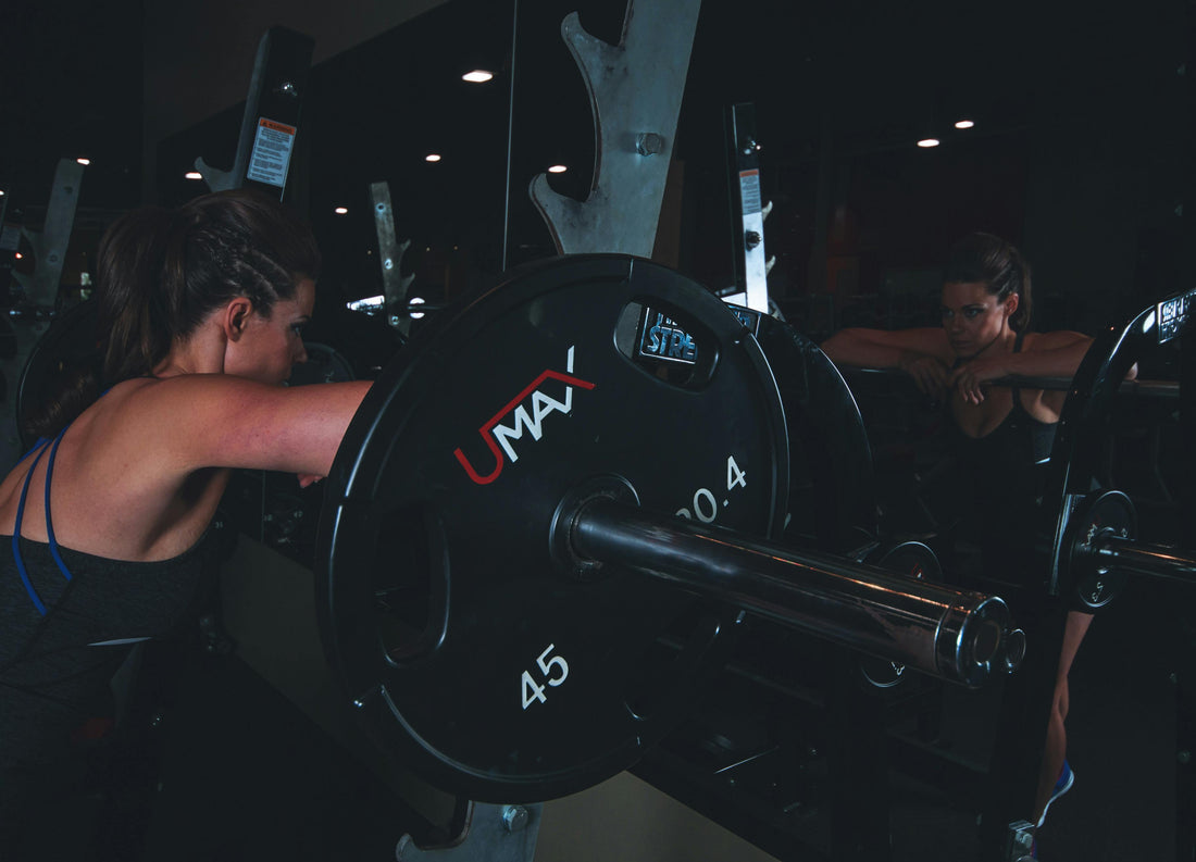 Woman leaning against a barbell on a squat rack