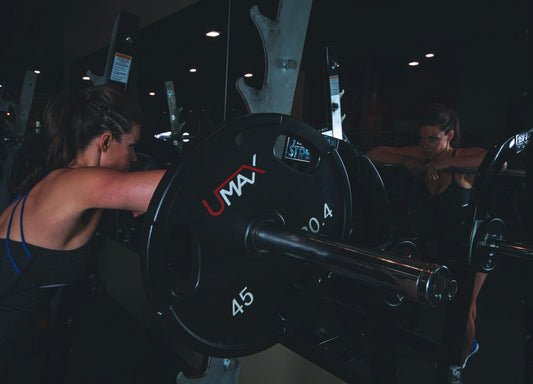 Woman leaning against a barbell on a squat rack